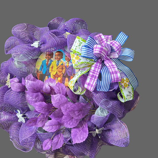 Purple decorative wreath with a bow and children's picture on a table.