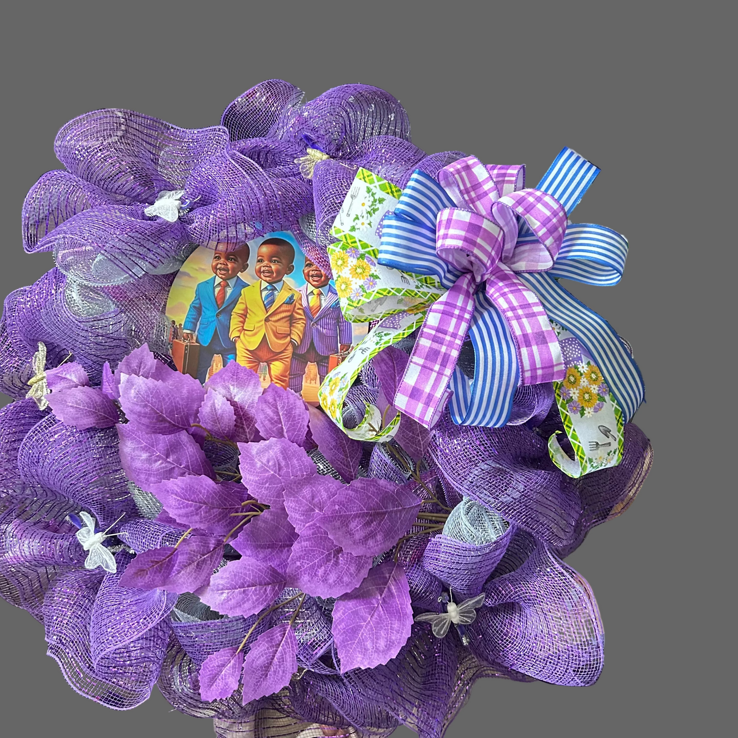 Purple decorative wreath with a bow and children's picture on a table.