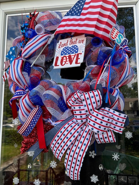 Decorative wreath with American flag elements and text on a window.